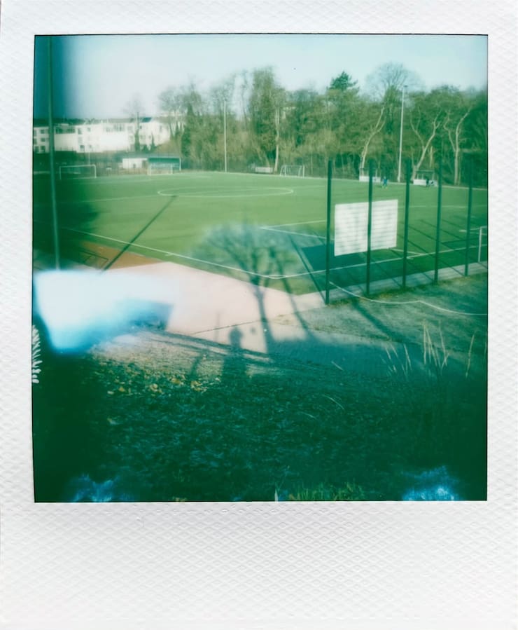A football field in the morning sun. Long shadows of trees and myself projecting onto it.