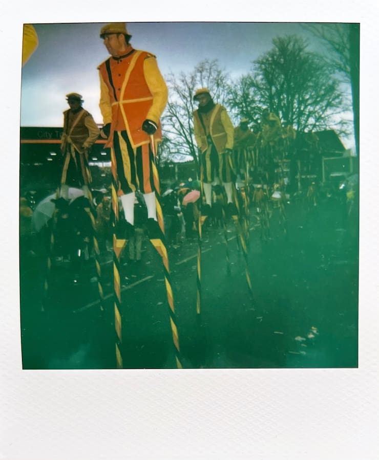 Men in black red yellow costumes on stilts.