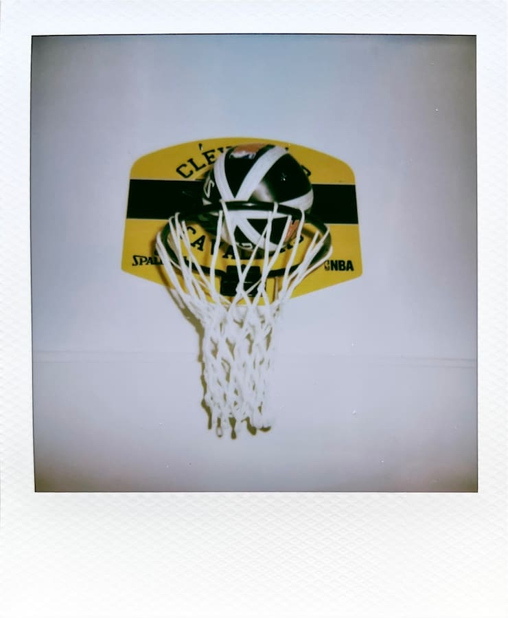 A little indoor baskeball basket and a ball about to fall
      in.