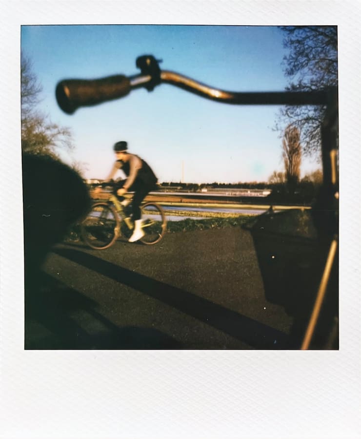 A speedy cyclist in the low evening sun. Parts of a bike in the
      foreground.
