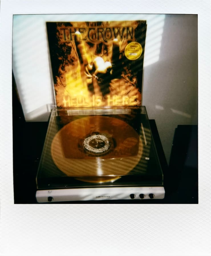 A vinyl sleeve on top of a record play, showing The Crown's
      Hell is Here album.
