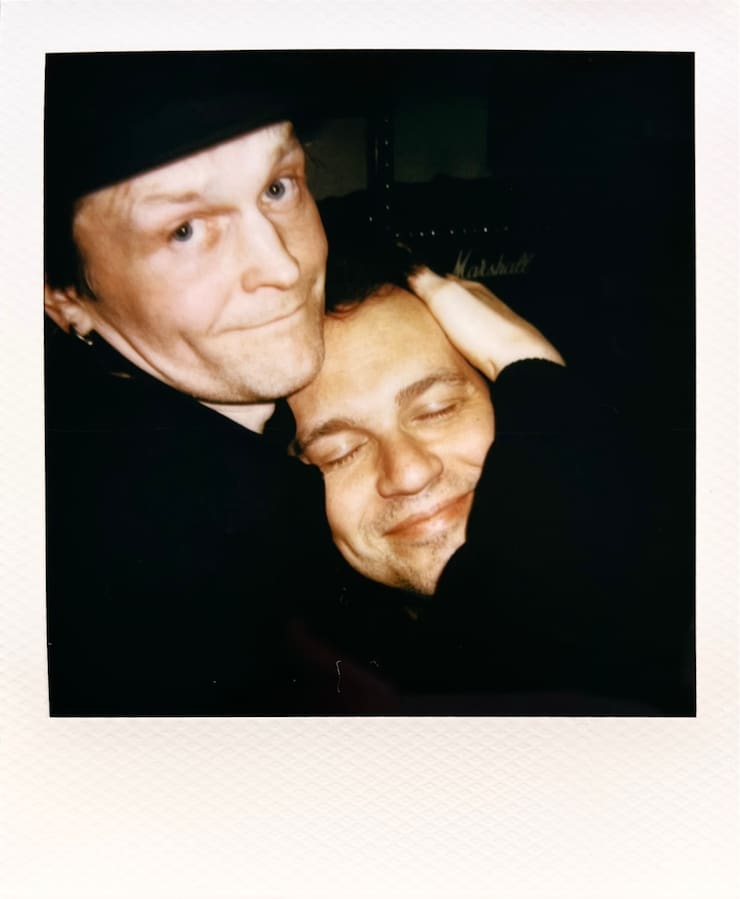 Two men. On holding the other's head in his arms.