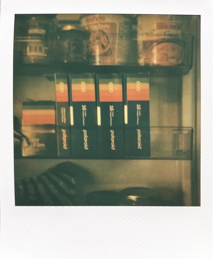 A fridge door, open. There‘s a few packs of Polaroid film to see.