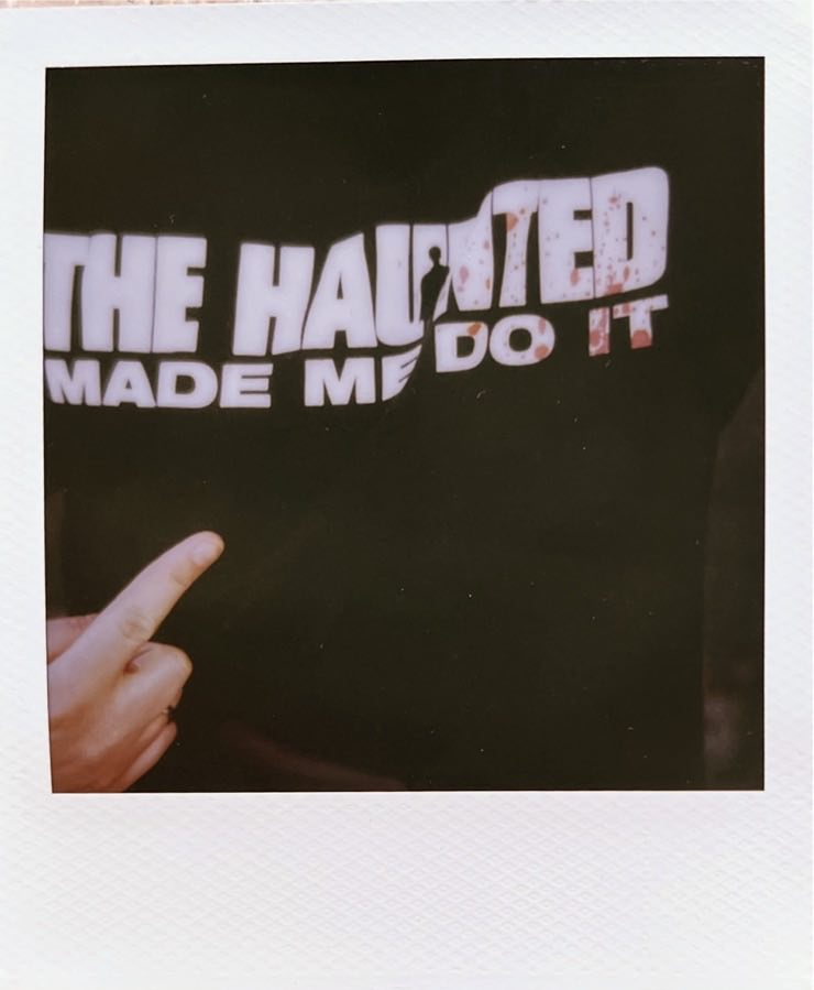 A hand pointing to its wearer’s shirt, saying The Haunted made me do it.