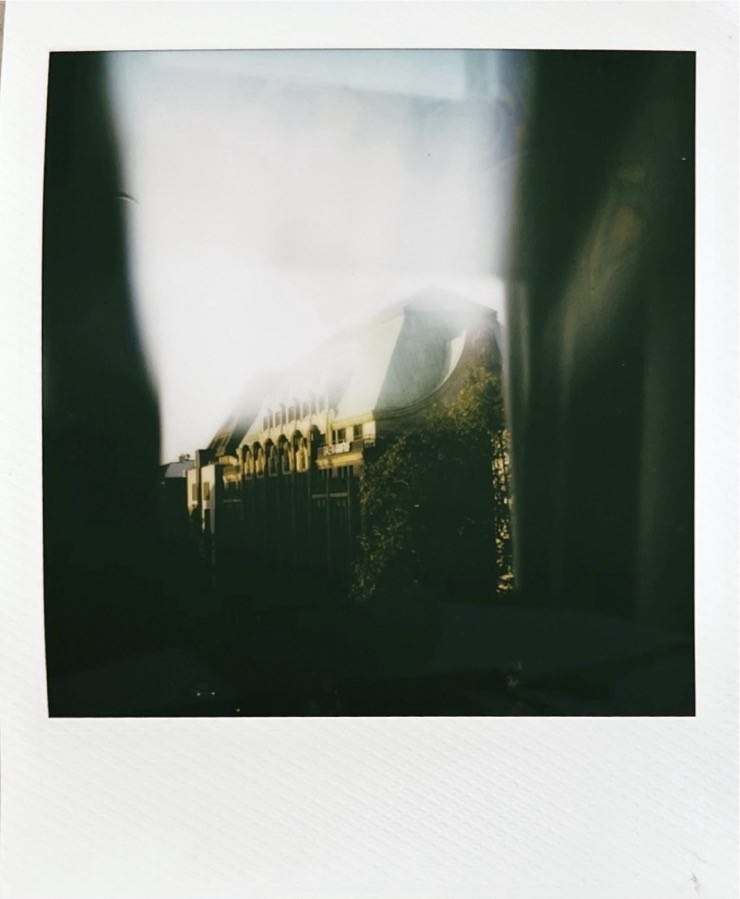 The top of a larger building illuminated by sunlight, shot through a window.