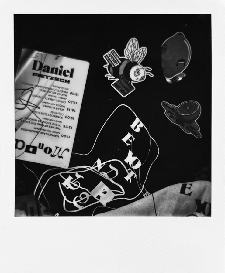 A badge, a T-Shirt, a bag, and stickers photographed from above.