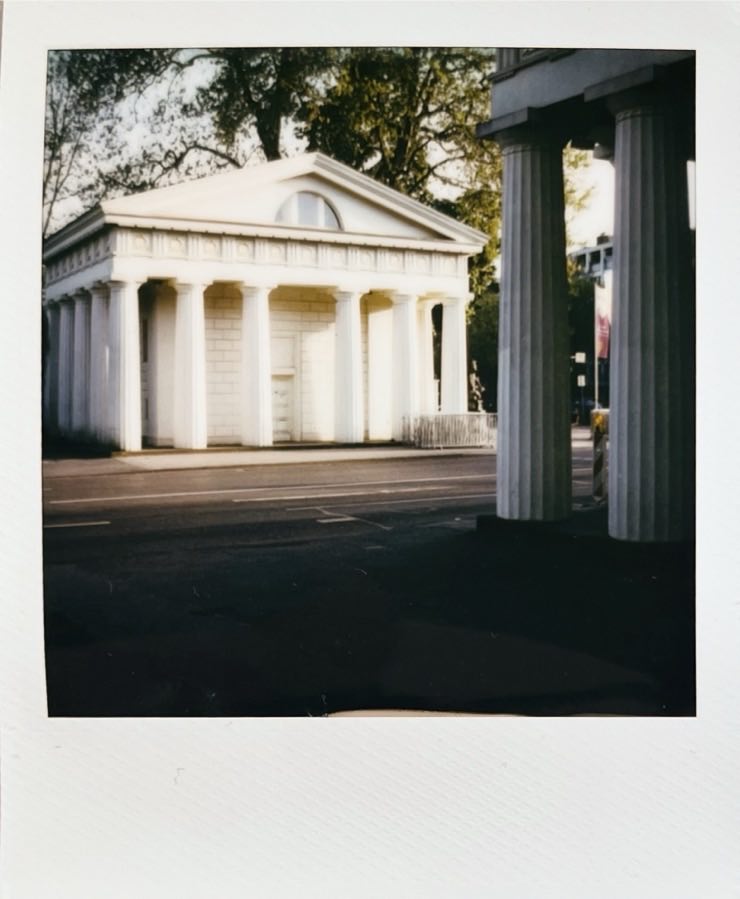 A white building with pillars, illuminated by the evening sun.