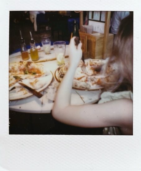 Two Neapolitan pizzas on a round table. A child slicing their pizza.