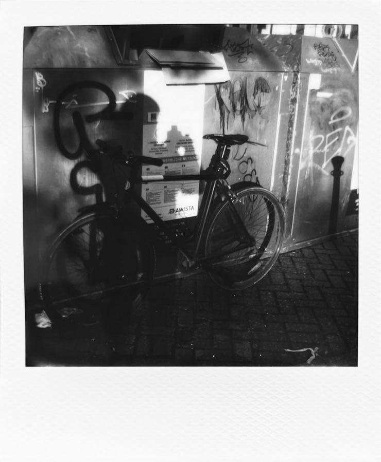 My singlespeed bike leaning against a container with my shadow on top.