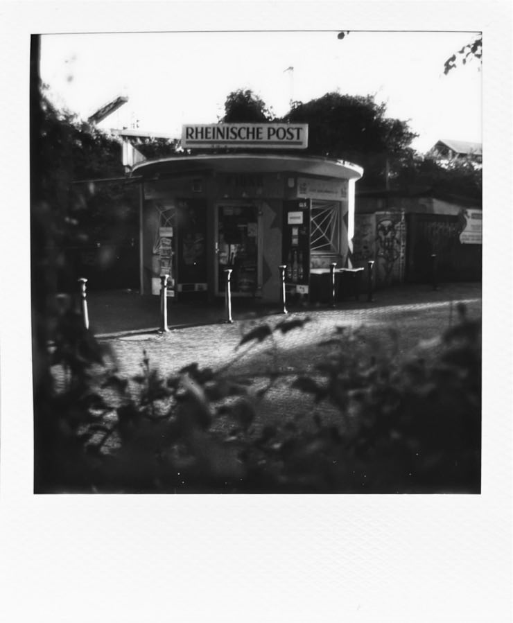 An image of a round detached German Kiosk at a cobblestone street.
