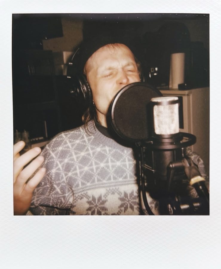 A singer with eyes closed, singing behind a microphone.