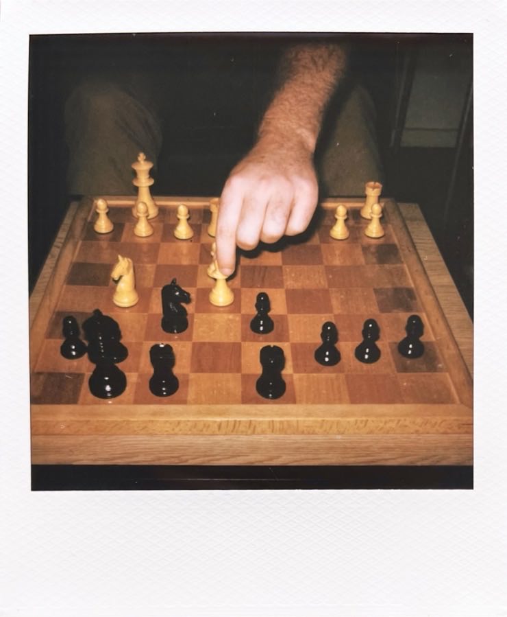 A chess board and a hand reaching in, making a move.