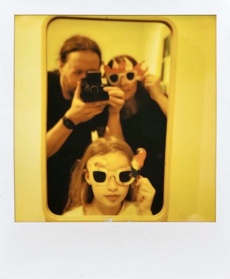 A man holding the camera and a woman and child with sunglasses on.