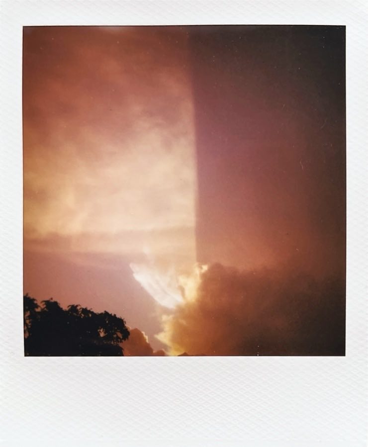 An evening sky with the sun illuminating the left half much more.