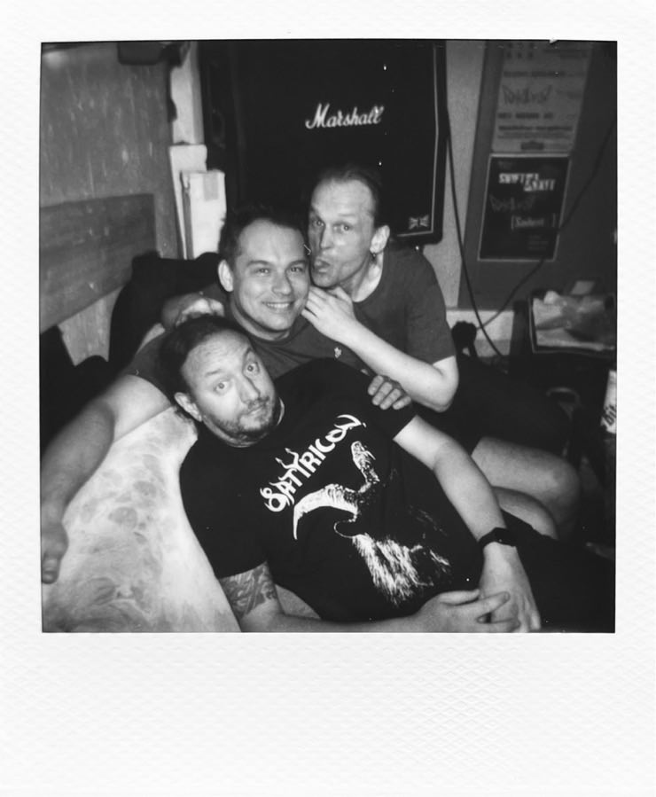 The three men of Forkalyst lying on a couch being silly.