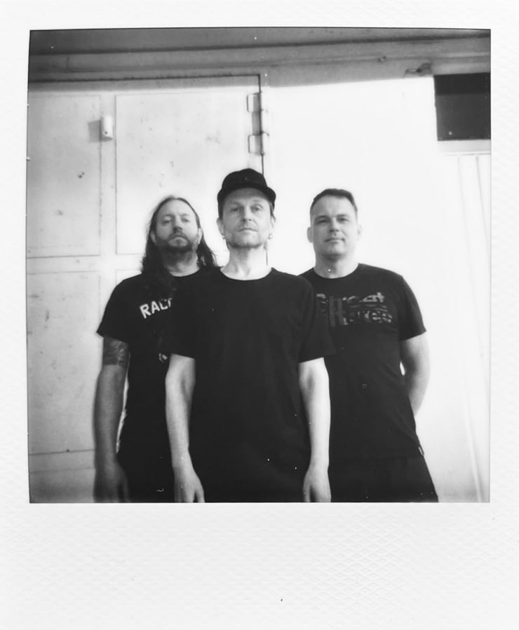 The three men of Forkalyst standing in front of a garage, looking into the camera.