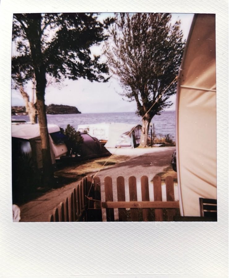 View from a tent onto a campground, with a view on a lake.
