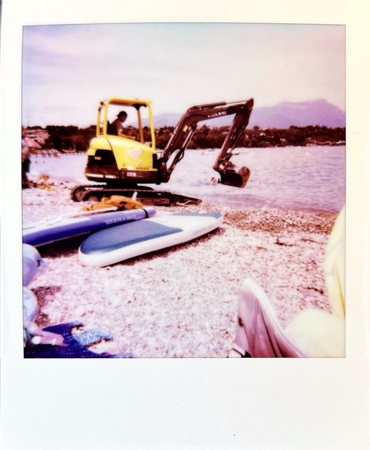 A yellow digger on a pebble beach.