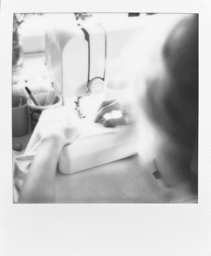 A sewing machine with kids hands holding a piece of fabric.